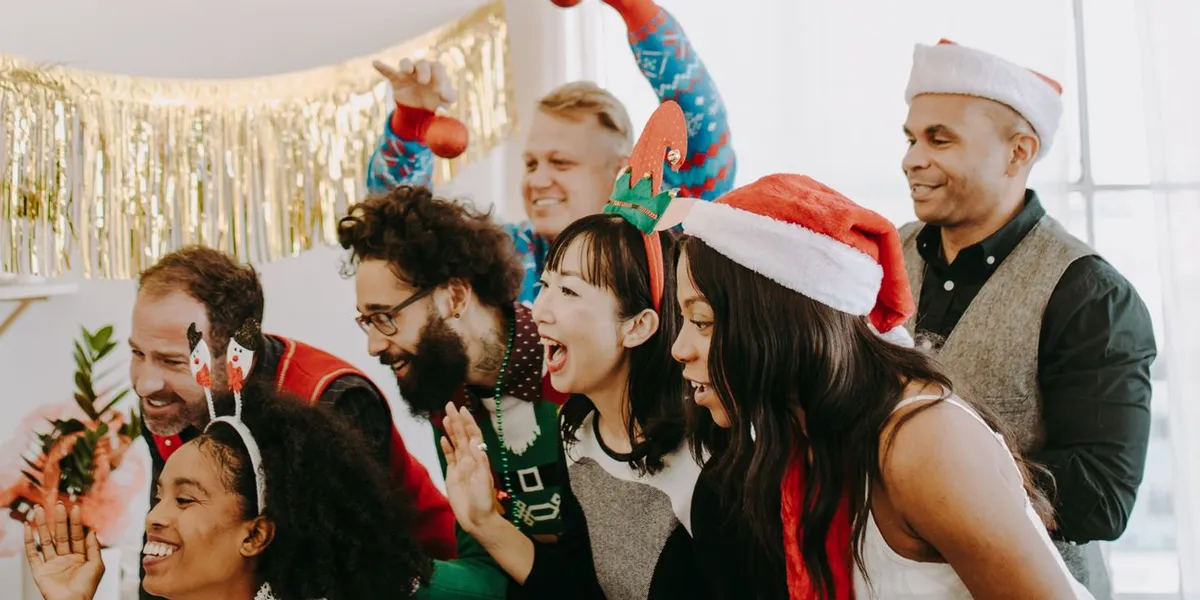 Illustration: colleagues in Santa hats and holiday sweaters in a decorated office