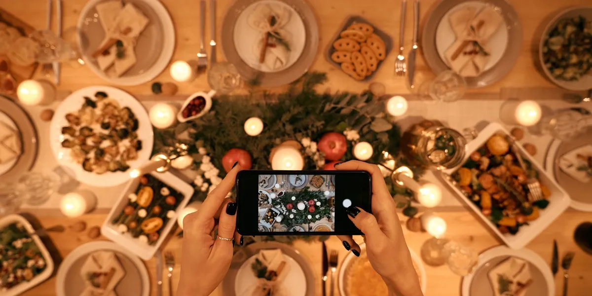 Illustration: hands photographing a festive holiday table with a phone