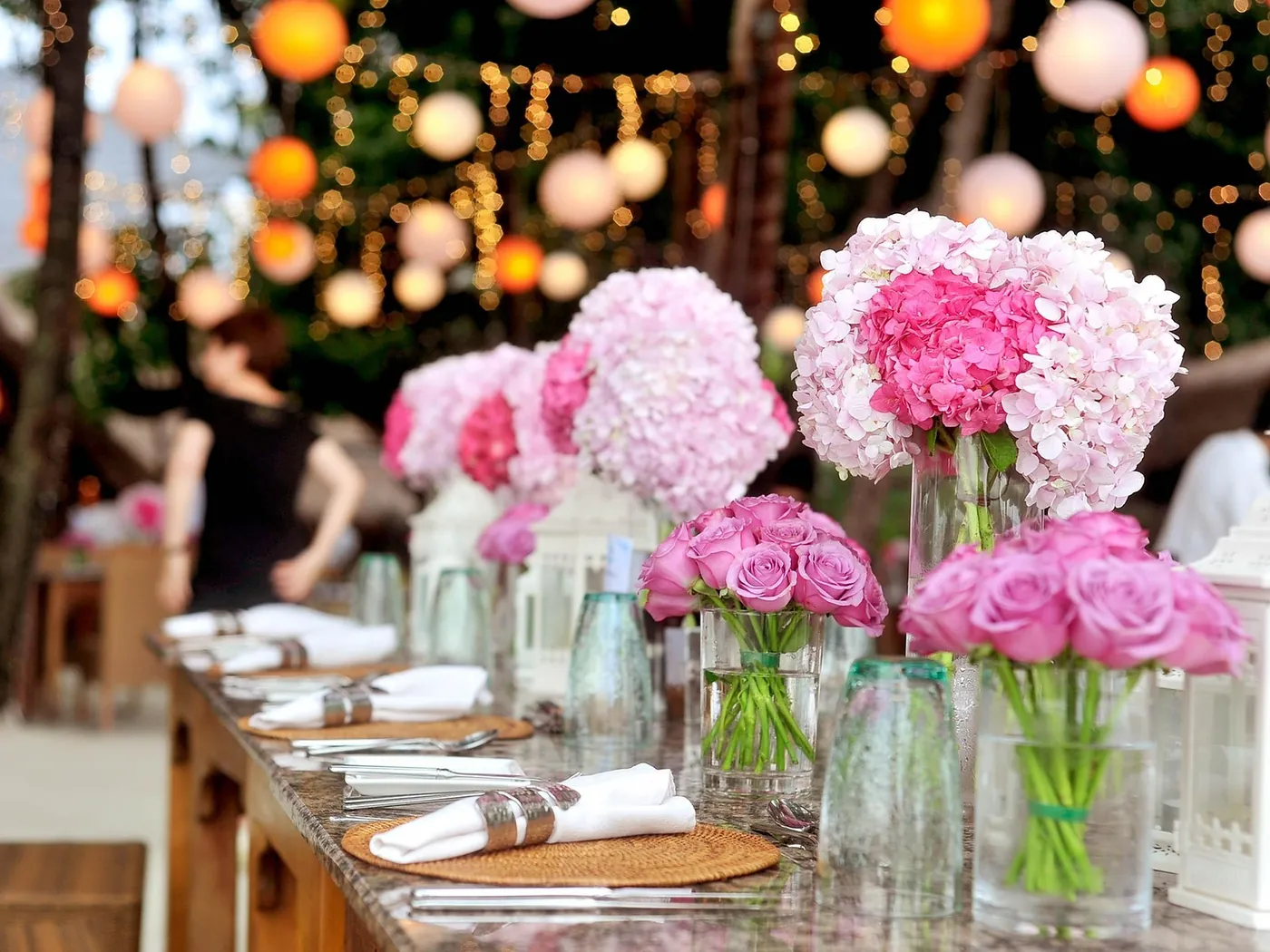 Wedding reception table with pink flowers under lanterns and string lights